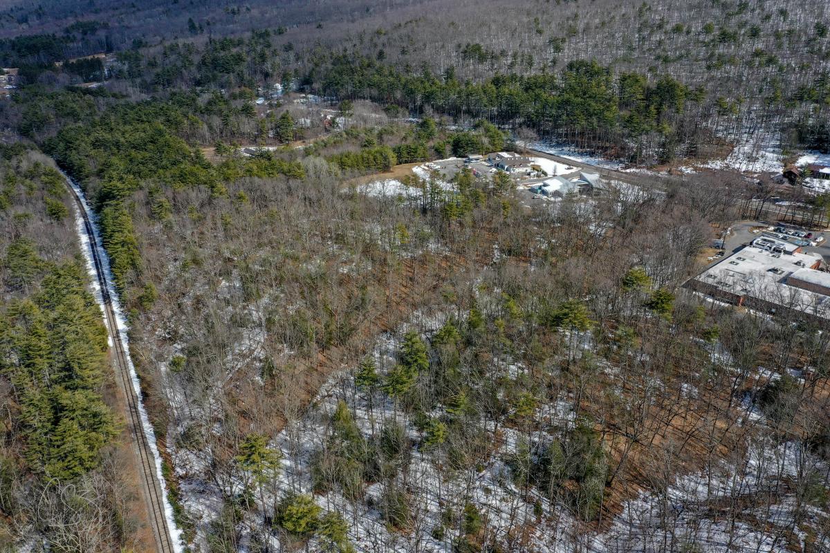 A drone photograph of a wooded area with a railroad running along the left side of the frame