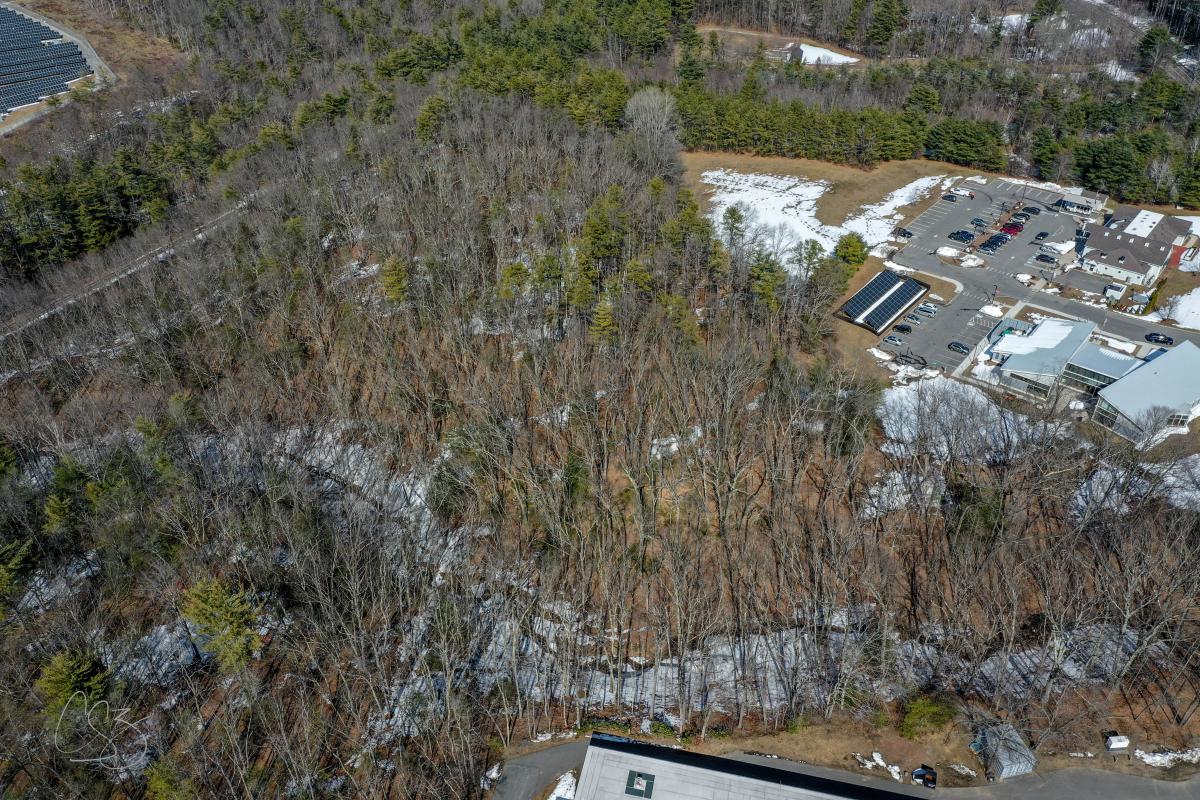 A drone photo of mostly wooded area with a small amount of developed area along the right side