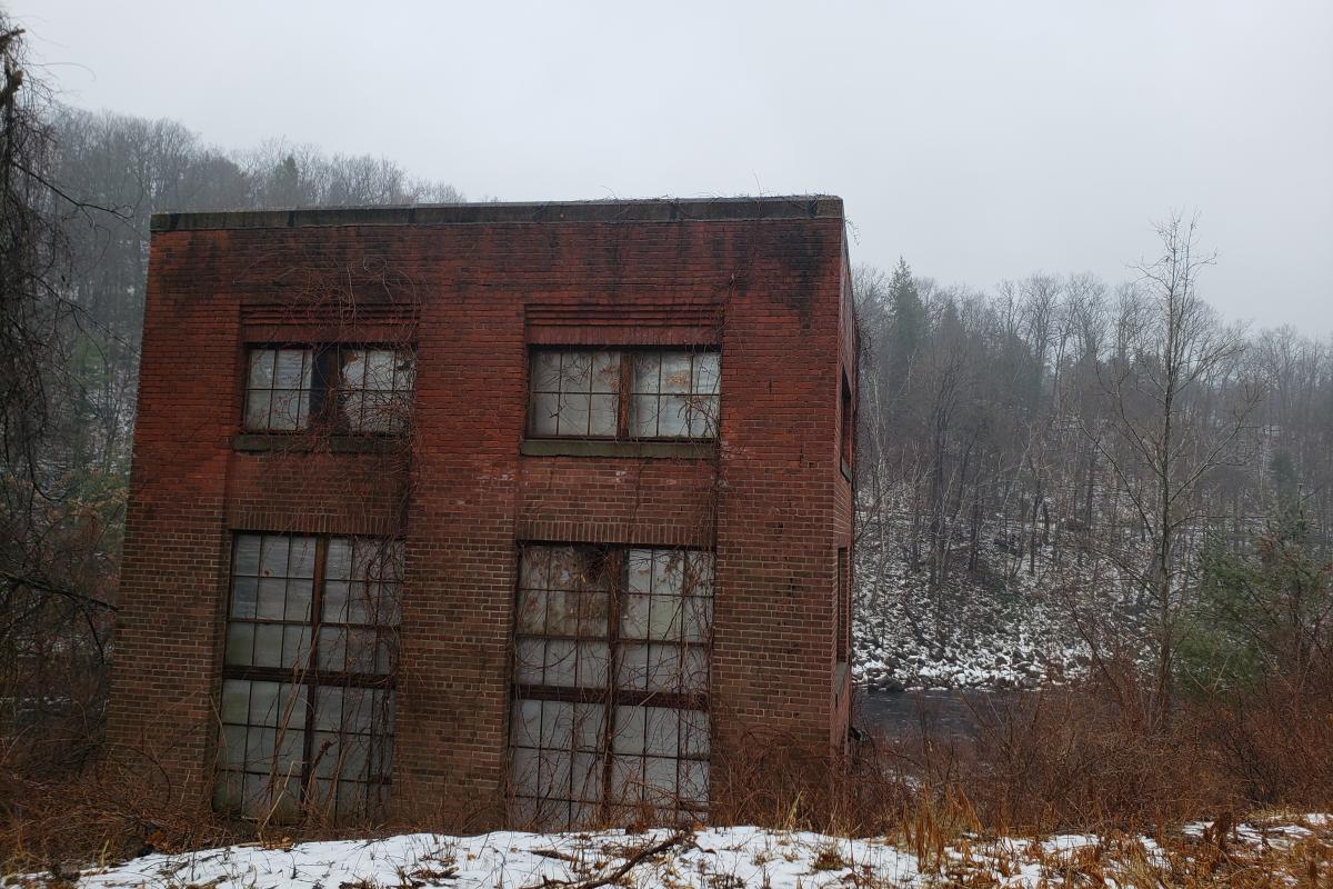 one small, abandoned, brick mill building on the edge of a stream on a foggy winter day