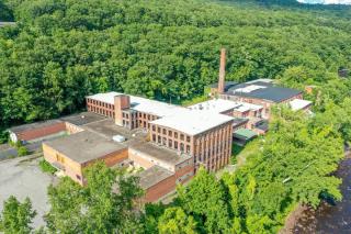 A drone photograph of the former IP Mill building during summer with lots of greenery